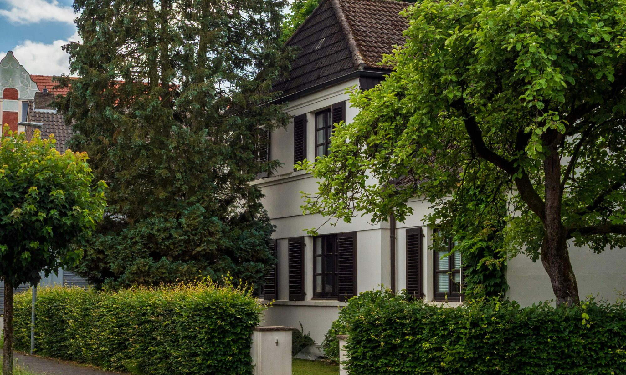 A picturesque suburban house surrounded by vibrant greenery under a blue sky.